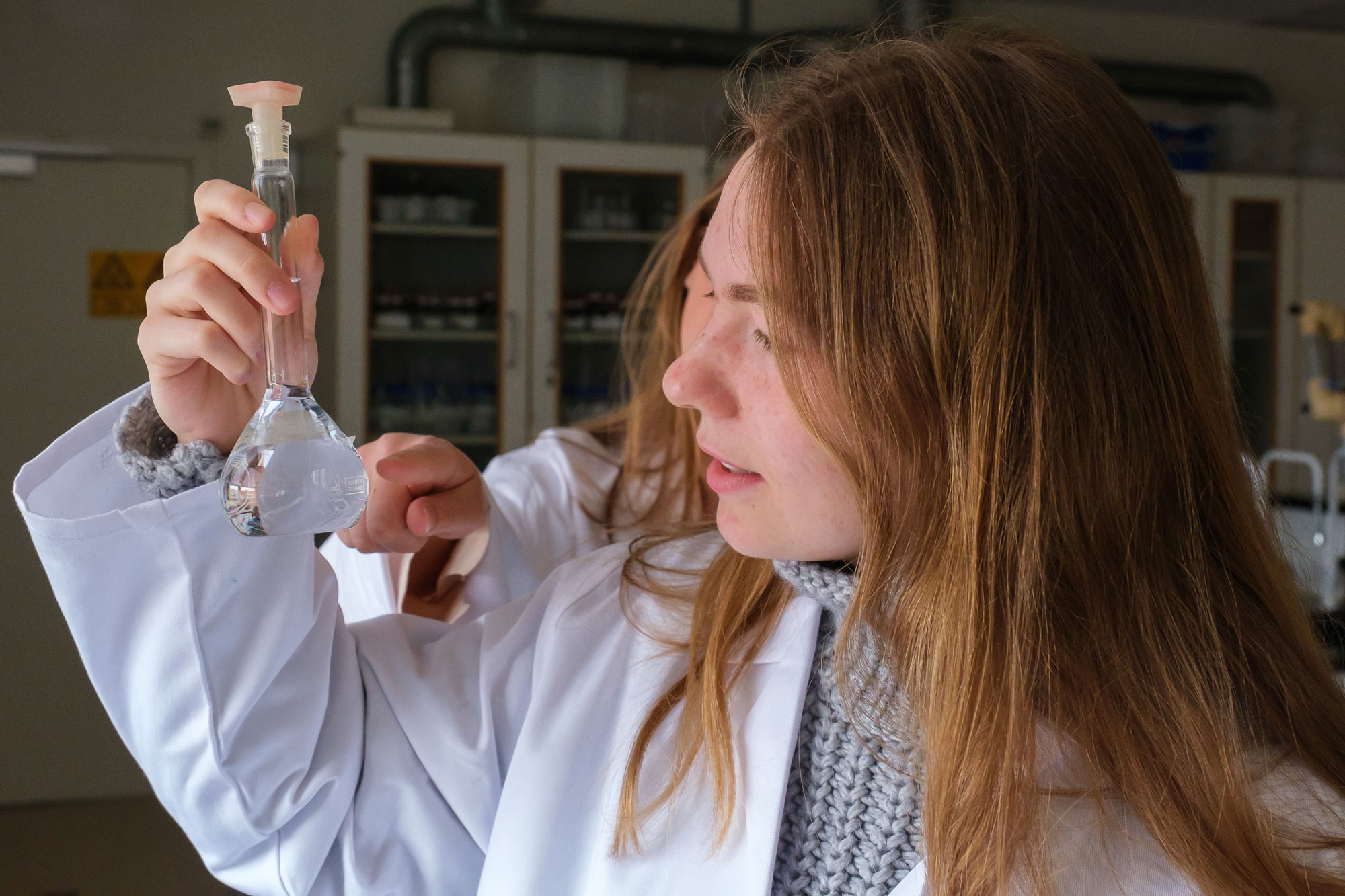 To piger nærstuderer kolbe i kemilokalet