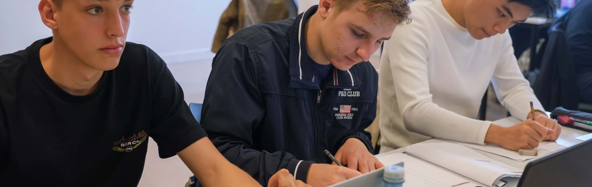 Tre drenge sidder ved siden af hinanden og laver opgaver i matematik