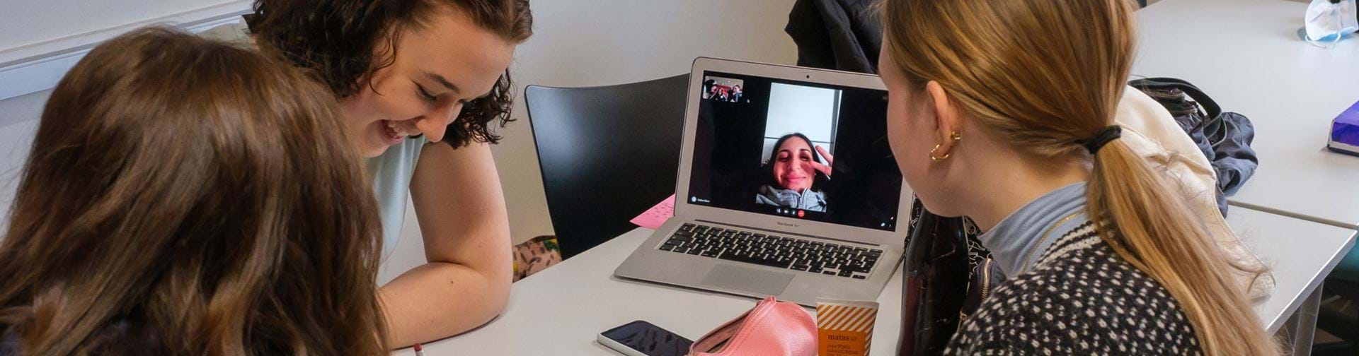 3 piger i gruppearbejde med en syg kammerat virtuelt på computeren