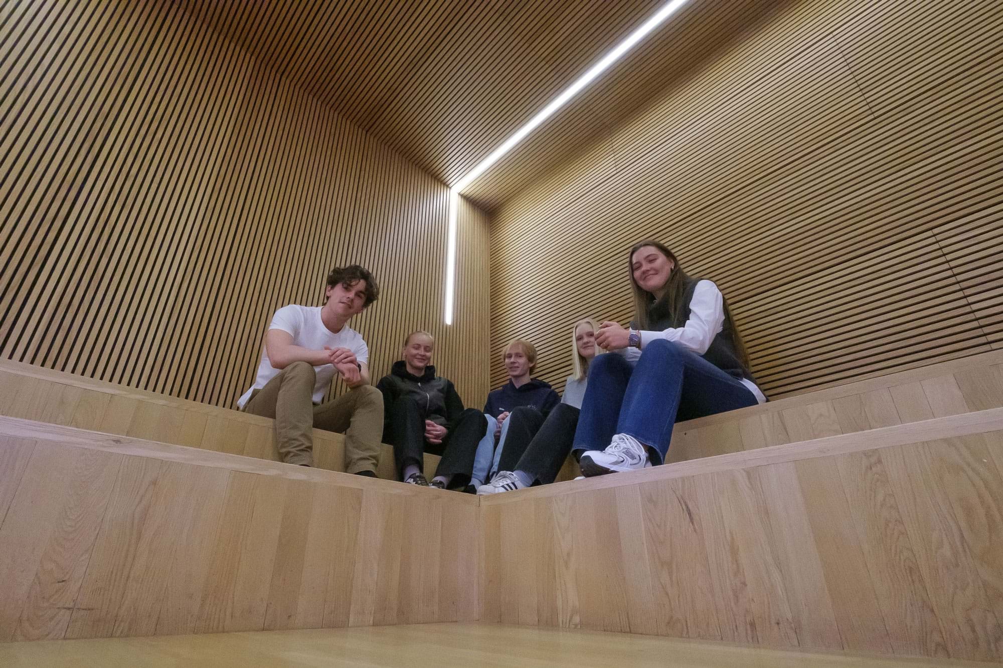 Fem elever sidder på indendørs trætrappe
