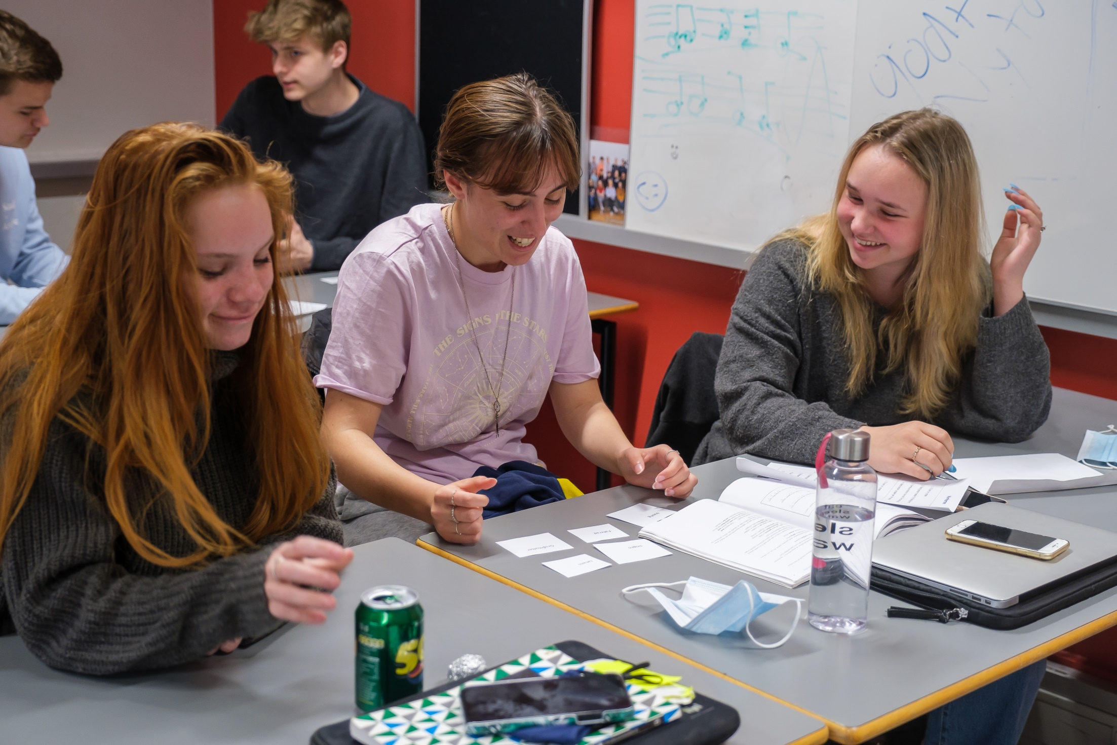 Tre piger sidder ved bord og laver gruppearbejde med små sedler