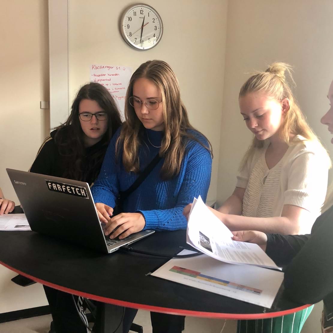 Fem piger står samlet om én computer