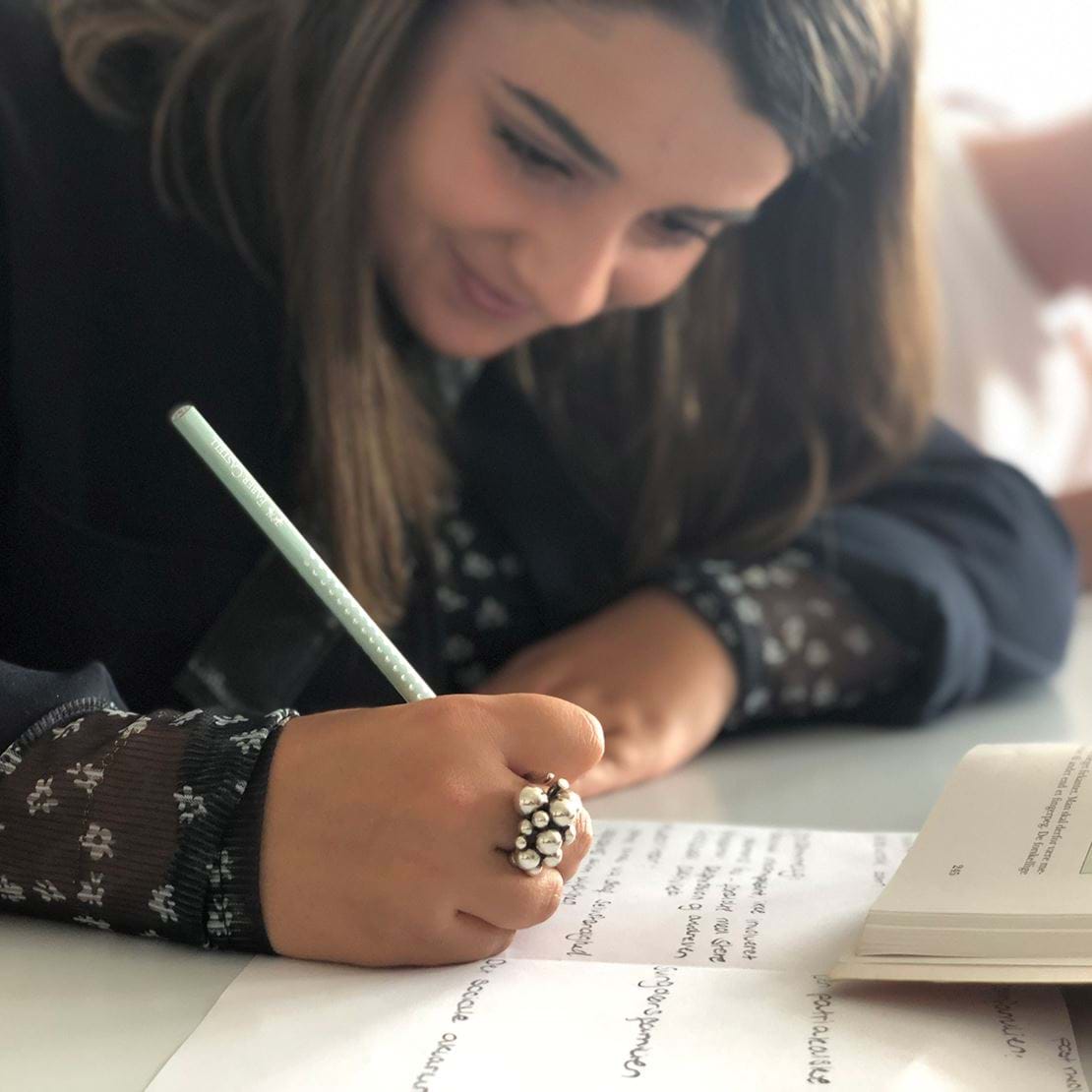 Pige laver skriftlige opgaver i hånden