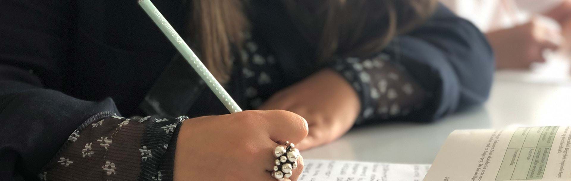 Pige skriver noter i hånden