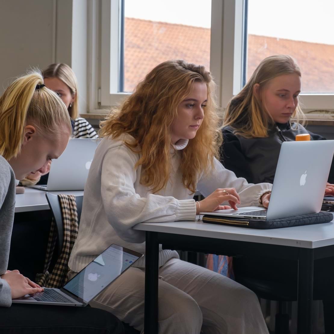 Tre piger skriver på hver deres bærbare computer