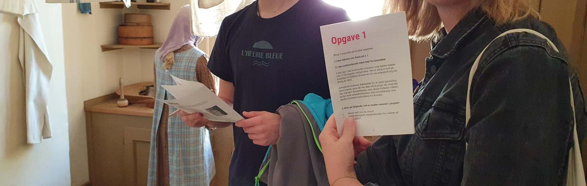 Ung mand og kvinde viser opgave hvorpå der står opgave 1