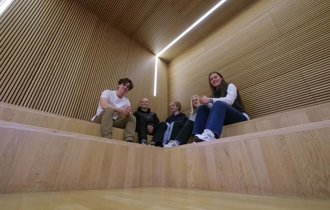 Fem elever sidder på indendørs trappe